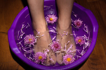 beauty female legs in a bath with flowers,aroma spa with medical